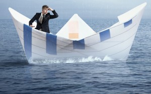 Businessman escapes from the crisis on a paper boat